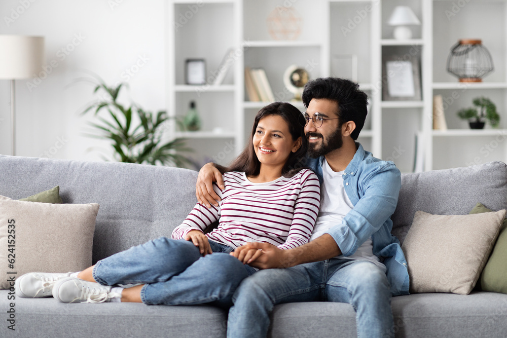 Loving eastern millennial man and woman cuddling at home