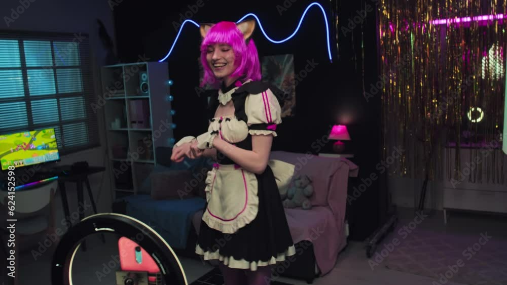 Modern Caucasian girl wearing cute cat maid cosplay outfit turning on smartphone camera then dancing while recording video