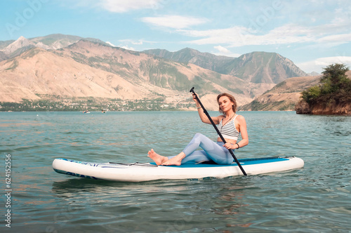 Woman on sup board. Mountain background. Healthy lifestyle