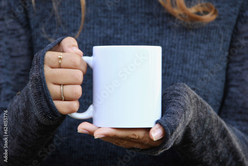 Girl is holding white mug in hands. Blank 11 oz white cup photo
