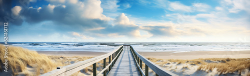 Panoramic landscape background banner panorama of sand dune  beach and ocean North Sea with blue sky  clouds  gulls and sunbeams