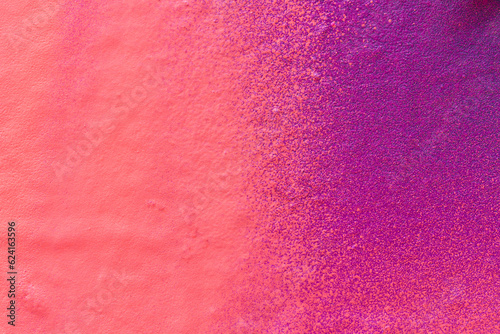 Macro close-up of a spray painted pink and purple wall with splashes. Abstract full frame textured splattered graffiti background with copy space.