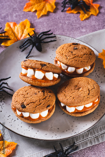 Halloween treats cookies with marshmallow teeth on a plate and spiders vertical view