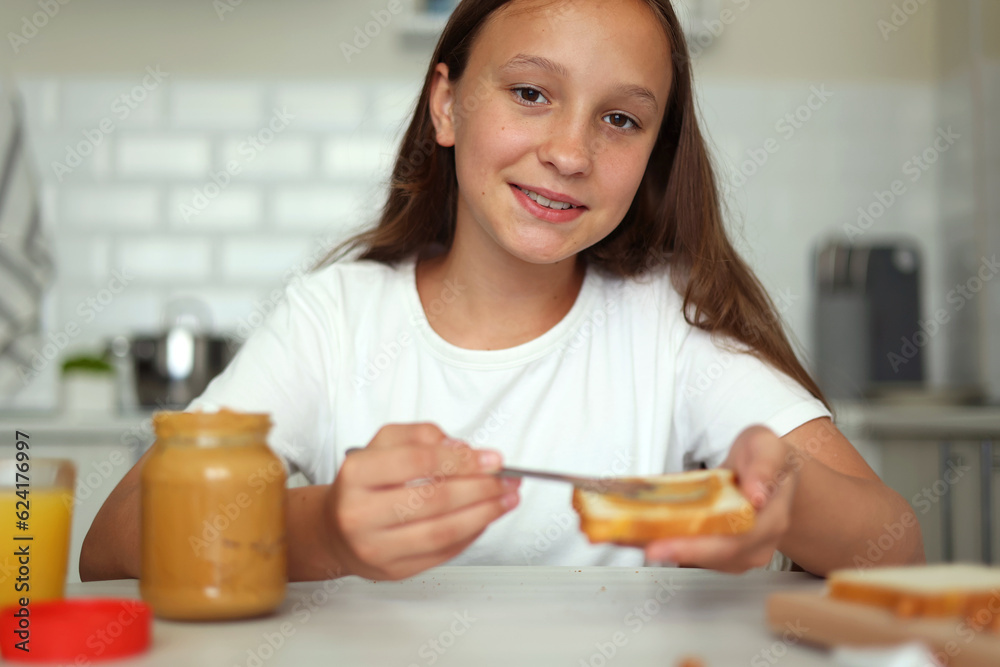 A girl in a good mood making a peanut butter sandwich in the kitchen A girl in a good mood making a peanut butter sandwich in the kitchen