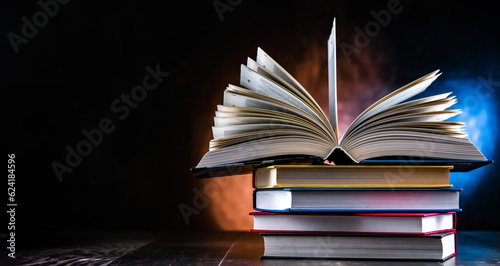 Foto A composition with an open book lying on a stack of other books