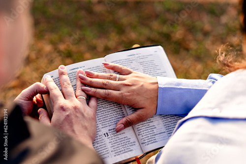 a couple's hands on a holy bible