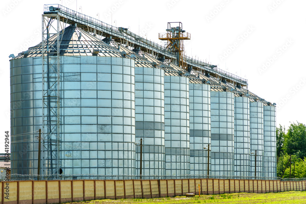 A large modern plant for the storage and processing of grain crops. view of the granary on a sunny day against the blue sky. End of harvest season. A large modern plant for the storage and processing of grain crops. view of the granary on a sunny day against the blue sky. End of harvest season.