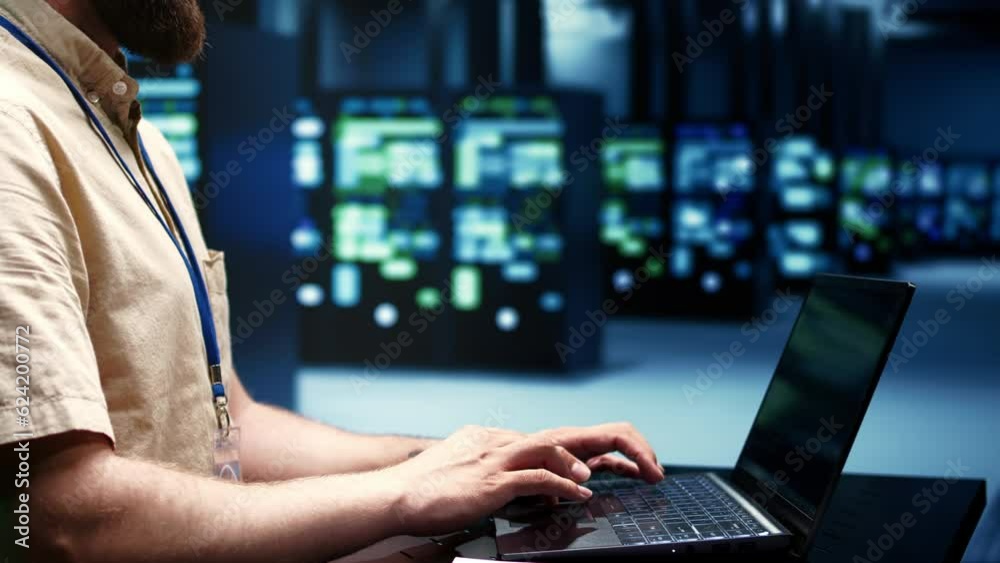 Supervisor running blade servers diagnostic tests and bug checking utilities to determine and repair software issues. Technician using laptop to survey critical systems, checking for flaws, close up Supervisor running blade servers diagnostic tests and bug checking utilities to determine and repair software issues. Technician using laptop to survey critical systems, checking for flaws, close up
