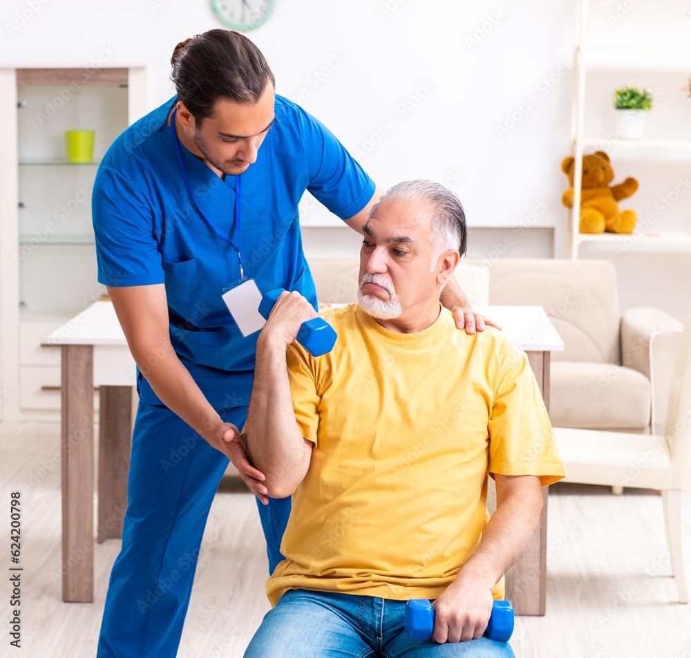 Obraz premium Young male doctor visiting old patient at home