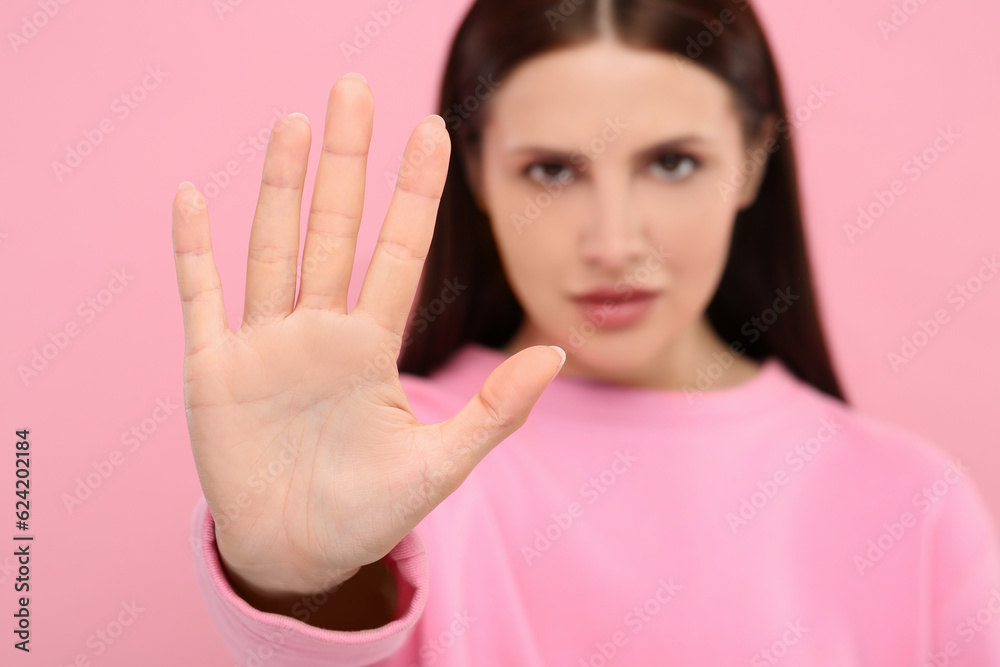 Woman showing stop gesture on pink background, selective focus Woman showing stop gesture on pink background, selective focus