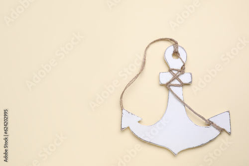 White anchor with hemp rope on beige background  top view. Space for text