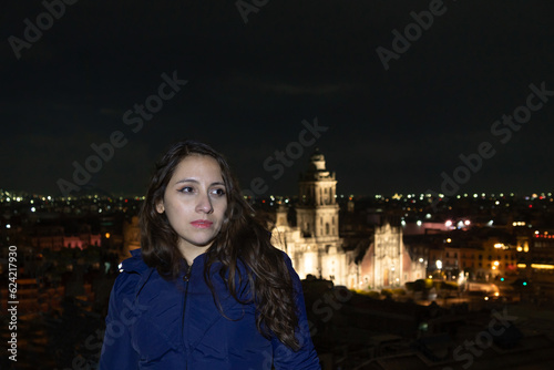 Young latin mexican girl enjoying the night roof top on Zocalo Down Town in Mexico City, with the background of Catedral Metropolitana