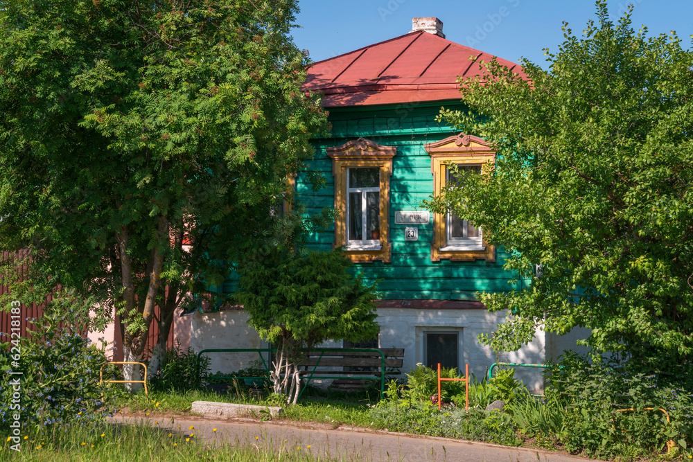 Fototapeta premium Russian traditional wooden house decorated with house carvings and a front garden on a sunny summer day, Suzdal, Vladimir region, Russia