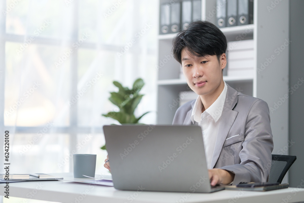 Businessman using laptop computer at desk in modern workplace.. Businessman using laptop computer at desk in modern workplace..