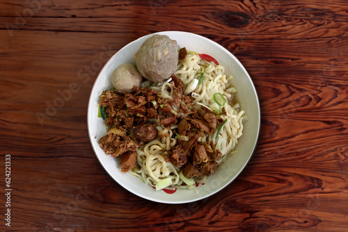 Indonesian famous street food Mie Ayam or chicken noodles served with meatballs, vegetables 
