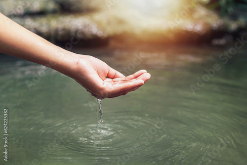 Woman's hand touching water in the midst of nature