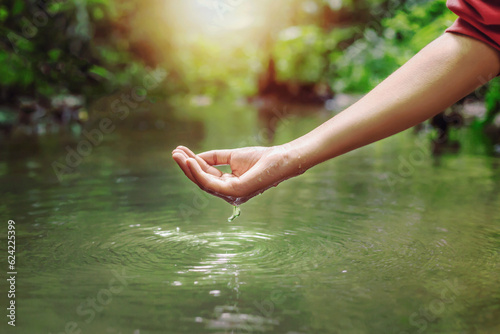 Woman s hand touching water in the midst of nature