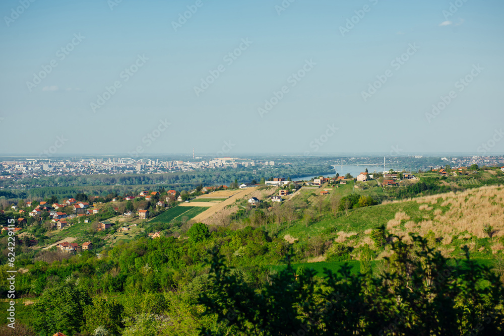 Fototapeta premium Panoramic view of the city of Novi Sad in Serbia from the top of Mount Fruska. View of the forest, fields, suburbs and city in spring sunny day