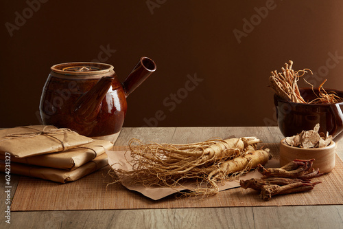 Porcelain pot with ginseng and rare herbs displayed on wooden table top and brown background. Medicines originating from ancient China, health-protecting foods. Front view, copy space photo