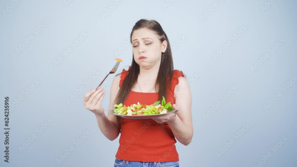 Person looking at vegetable on fork with unhappy expression. Difficulty dieting.