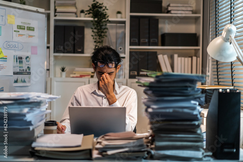 Frustrated Asian businessman worker work on table in office workplace. 