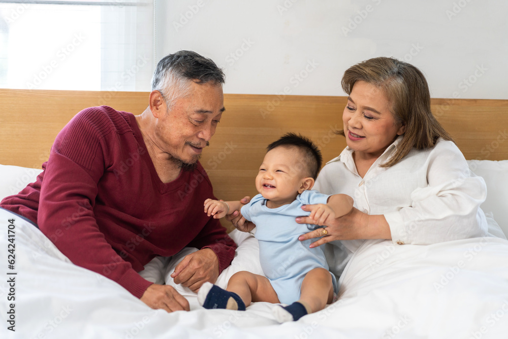 Portrait of happy love asian grandfather with grandmother playing with asian baby on bed, senior, insurance.Big family love with their laughing grandparents smiling together.Family and togetherness Portrait of happy love asian grandfather with grandmother playing with asian baby on bed, senior, insurance.Big family love with their laughing grandparents smiling together.Family and togetherness