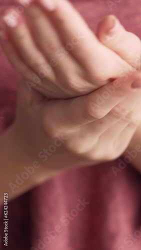 Vertical video. Hands treatment. Moisturizing care. Smooth skin. Nourishing cosmetic. Woman wrapped in towel with delecate manicure applying skincare cream product after shower. photo