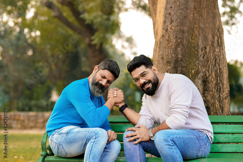 Two indian man in playful mood playing arm wrestling at park.