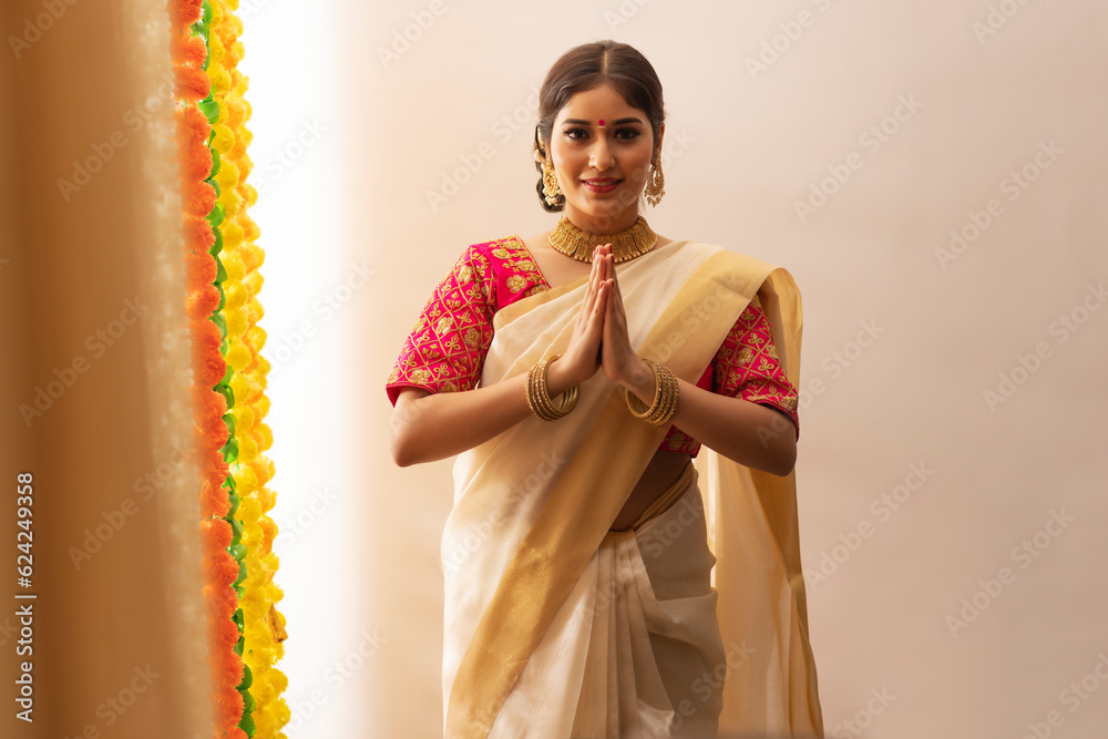 Φωτογραφία South Indian woman in white saree greeting on the occasion of Onam