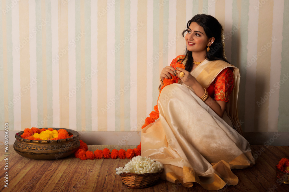 Φωτογραφία Woman in white saree garlanding flowers to celebrate Onam