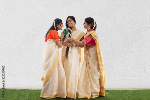 South Indian women in white saree standing together and talking on Onam