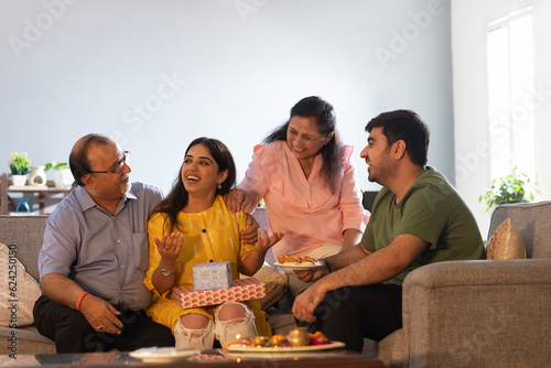 Happy Indian family sitting together at home and talking to each other on Raksha Bandhan