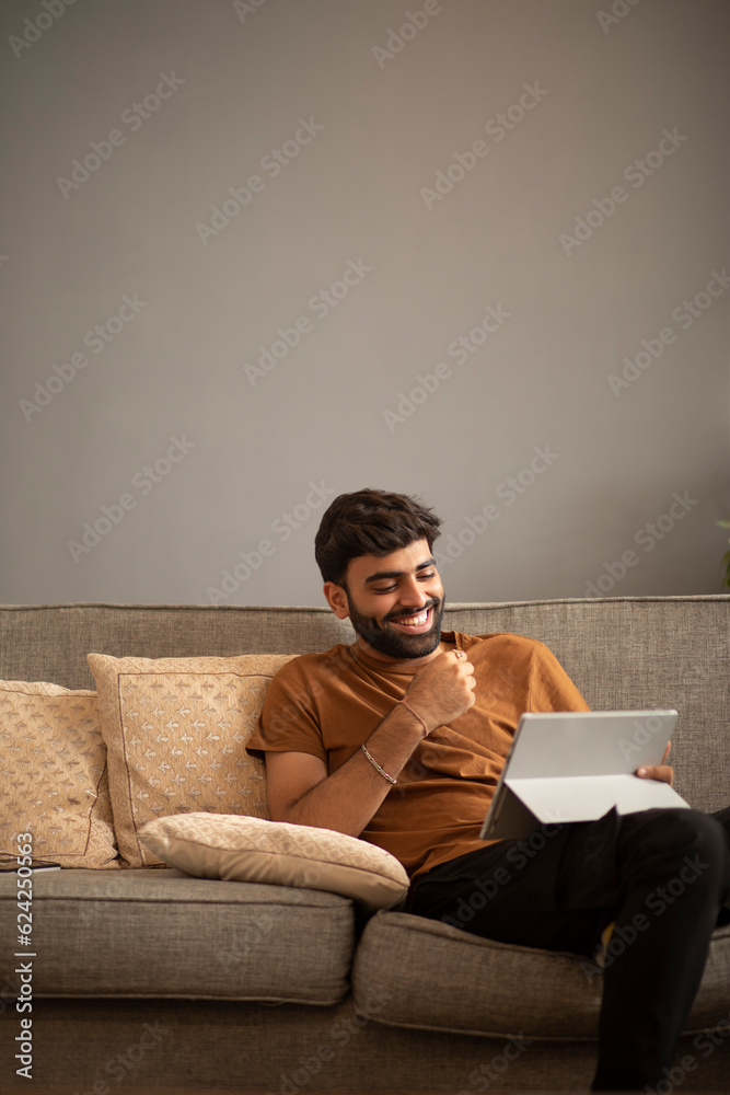 Young man using digital tablet while sitting on sofa in living room Young man using digital tablet while sitting on sofa in living room