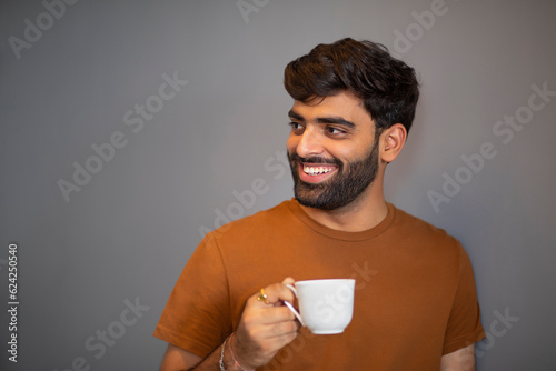 Portrait of cheerful man drinking tea against grey backgroiund photo