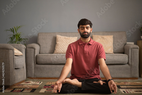 Young man meditating in living room