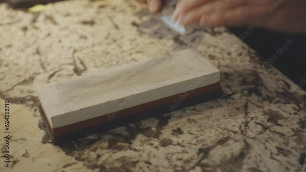 Close Up Of Hands Sharpening A Small Knife With Whetstone