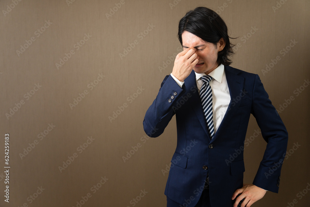 目頭を押さえる若いビジネスマン