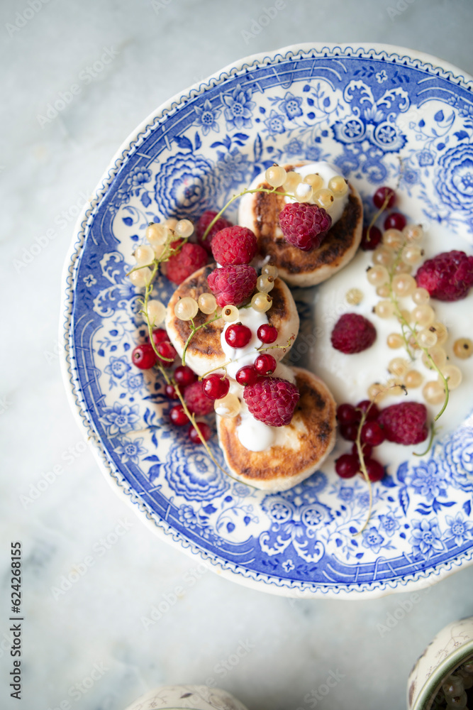 vintage plate with cottage cheese pancakes and berries. syrniki with greek yogurt, raspberries and currants.	