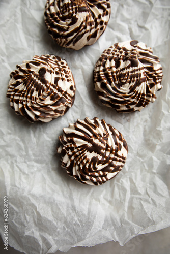 white zephyr covered with chocolate icing close-up. vanilla marshmallow with chocolate on crumpled paper top view.