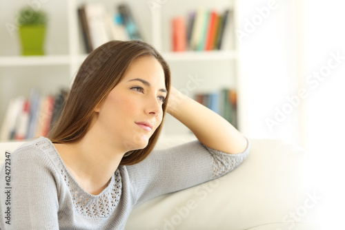 Pensive woman sitting on a couch at home