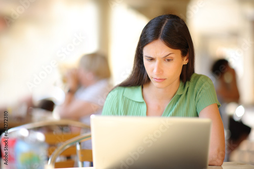 Suspicious woman using laptop in a restaurant photo