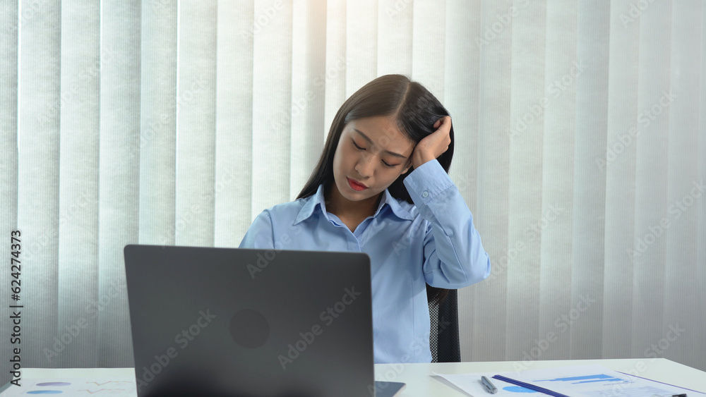 Asian woman sitting and working has a headache.