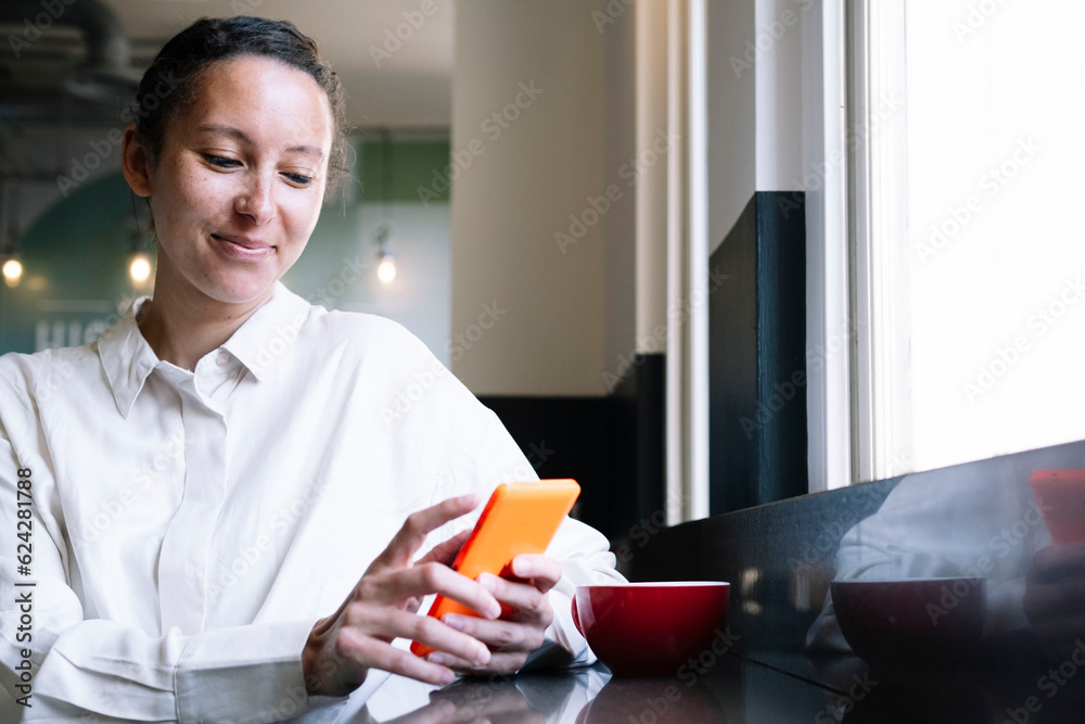 Smiling businesswoman using smart phone in cafe