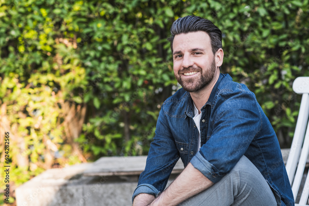 Happy man sitting in front of plants Happy man sitting in front of plants