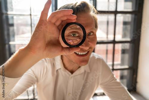 Happy mature businessman looking through magnifying glass photo
