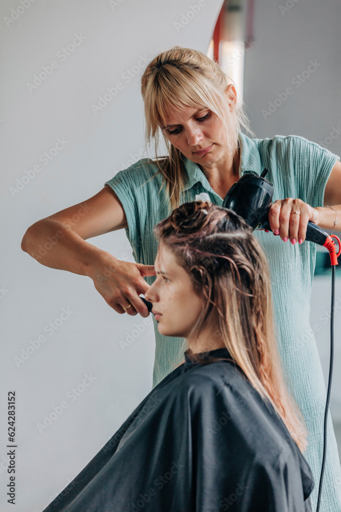 Hairdresser blow drying client's hair in salon Hairdresser blow drying client's hair in salon