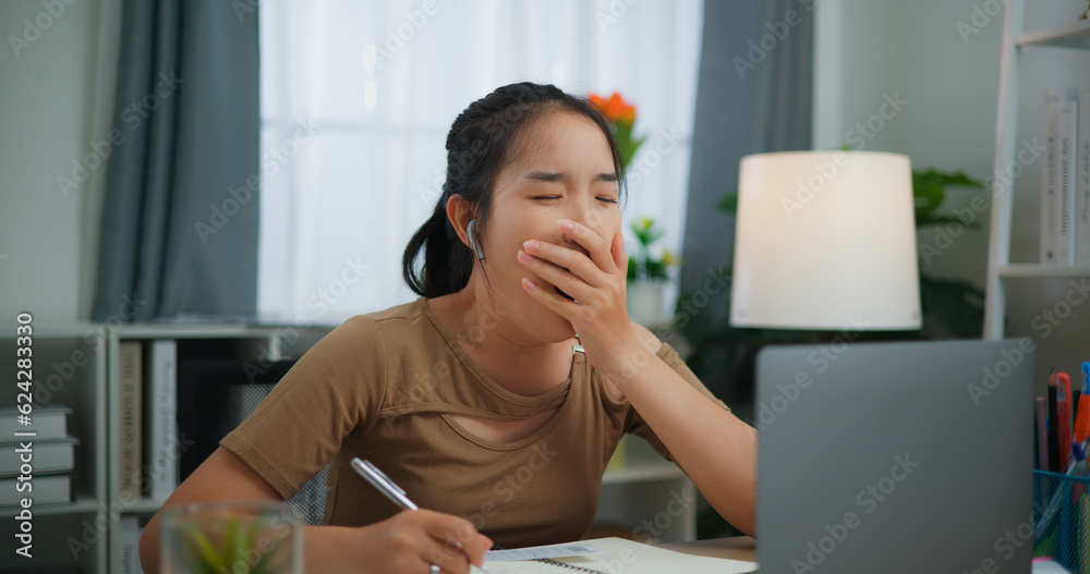oung Asian woman working with a laptop and writing on paper on a desk oung Asian woman working with a laptop and writing on paper on a desk