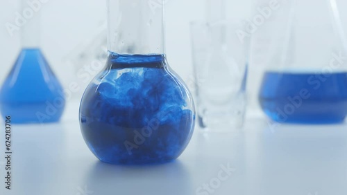 Blue liquid substance dissolve in a  glass flask. Concept for advertising perfume and cosmetic products. Mixing blue ink with water in a large laboratory glass test tube. 