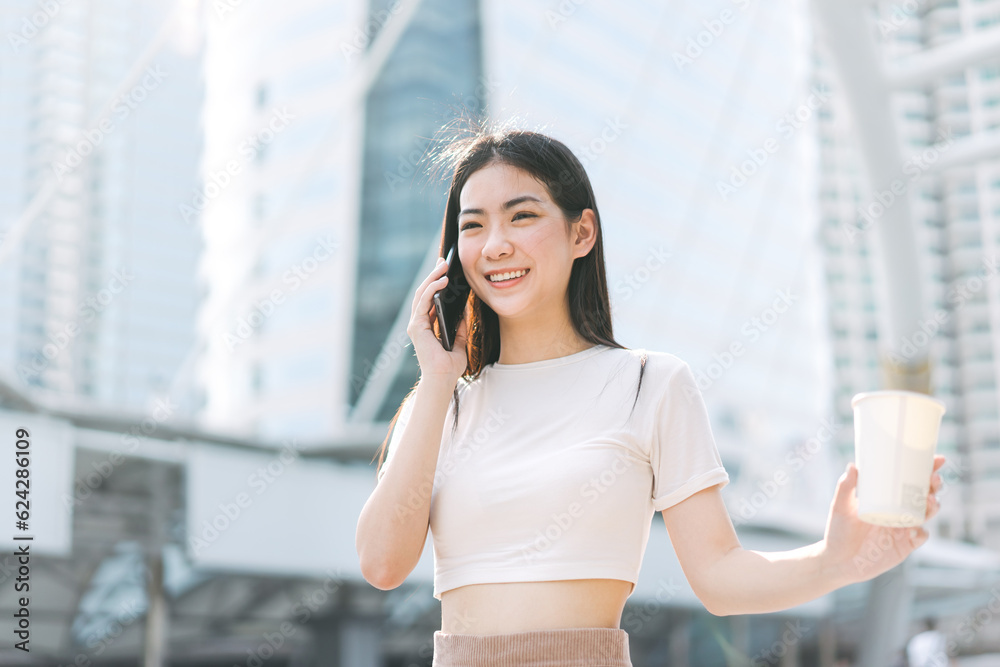 Asian business single woman using smart phone talking holding coffee cup in the city