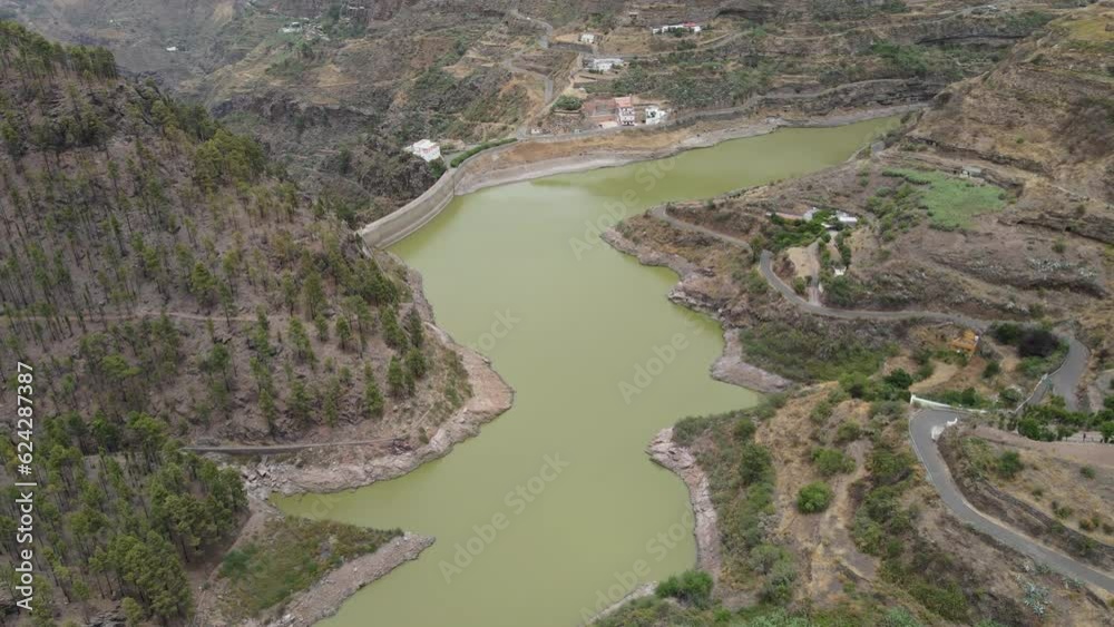 Los Perez y Lugarejos dam: aerial view traveling in to the fantastic dam with green waters and the grove that surrounds it. Located in Artenara, Gran Canaria island on a sunny day. Los Perez y Lugarejos dam: aerial view traveling in to the fantastic dam with green waters and the grove that surrounds it. Located in Artenara, Gran Canaria island on a sunny day.